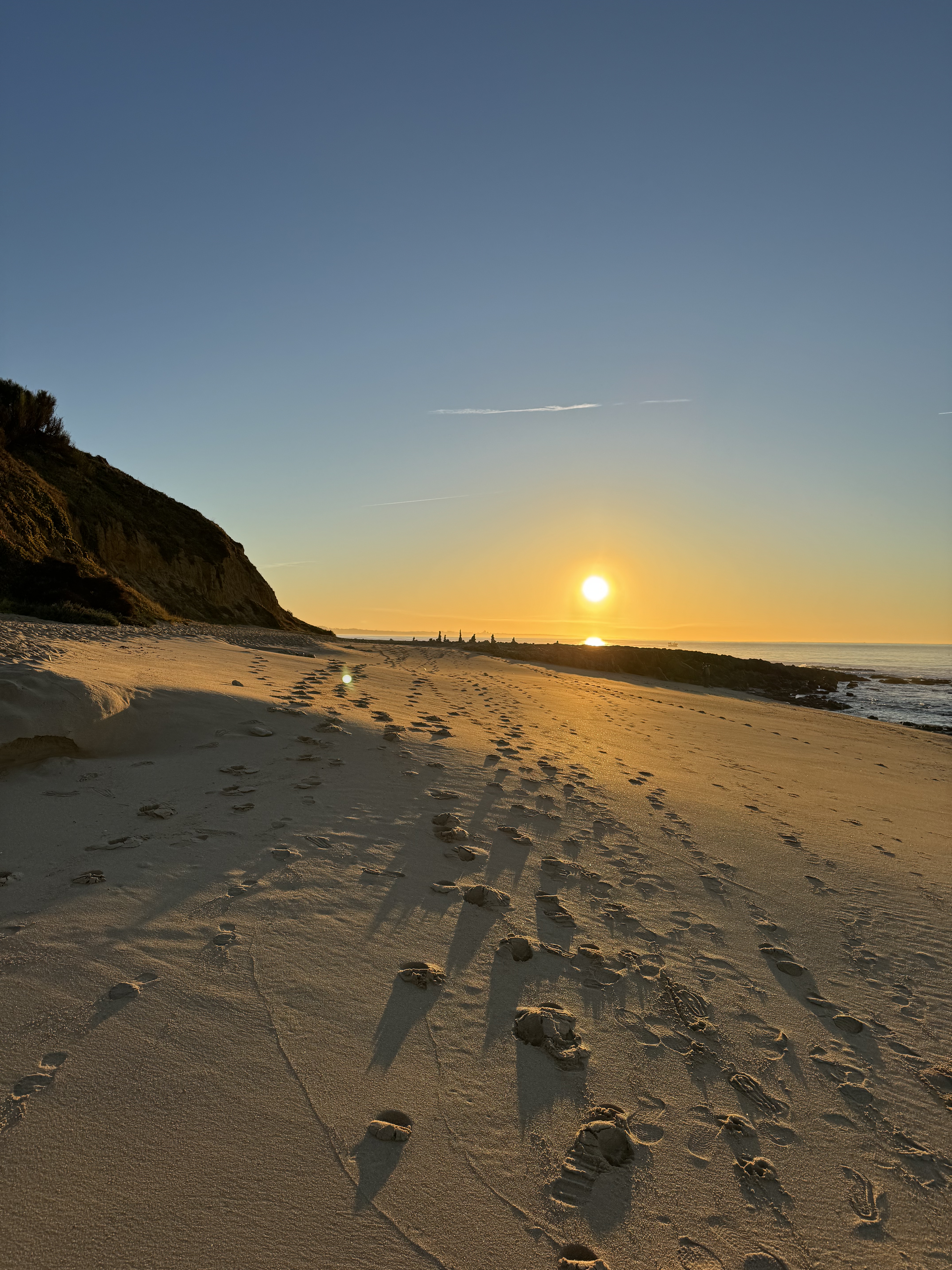 Fußabdrücke im Sand beim Sonnenaufgang