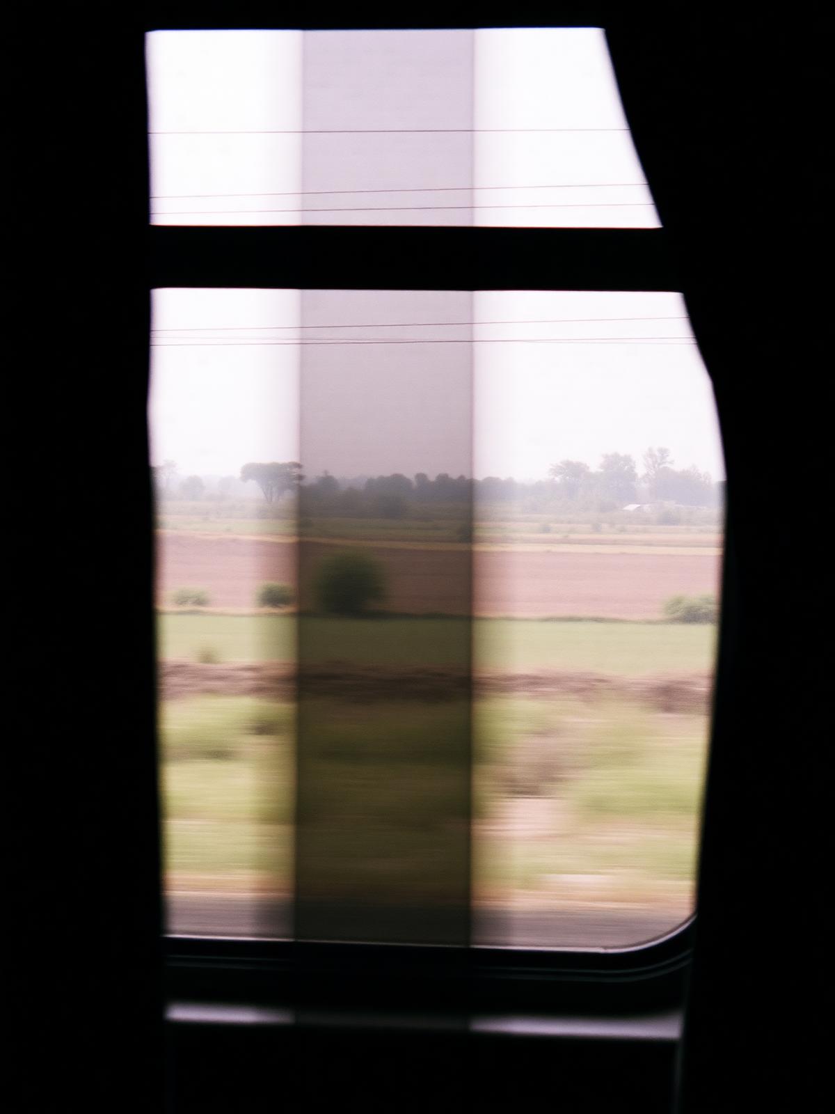 Blick aus einem fahrenden Zug auf Felder